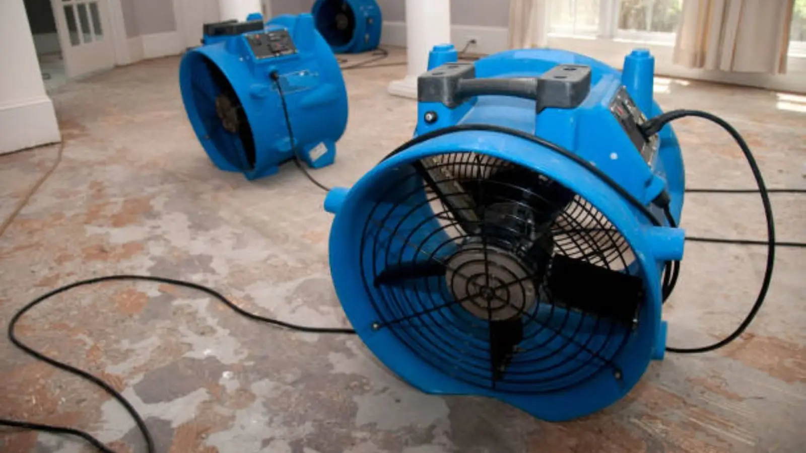 Large blue air mover drying a floor, the kind of equipment priced into a restoration job